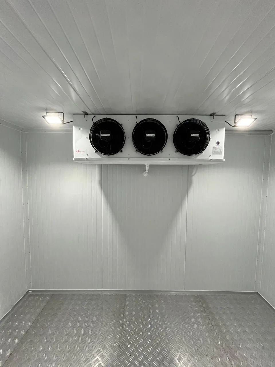 Cámara frigorífica terminada con paneles blancos, evaporador de tres ventiladores y piso de aluminio estriado