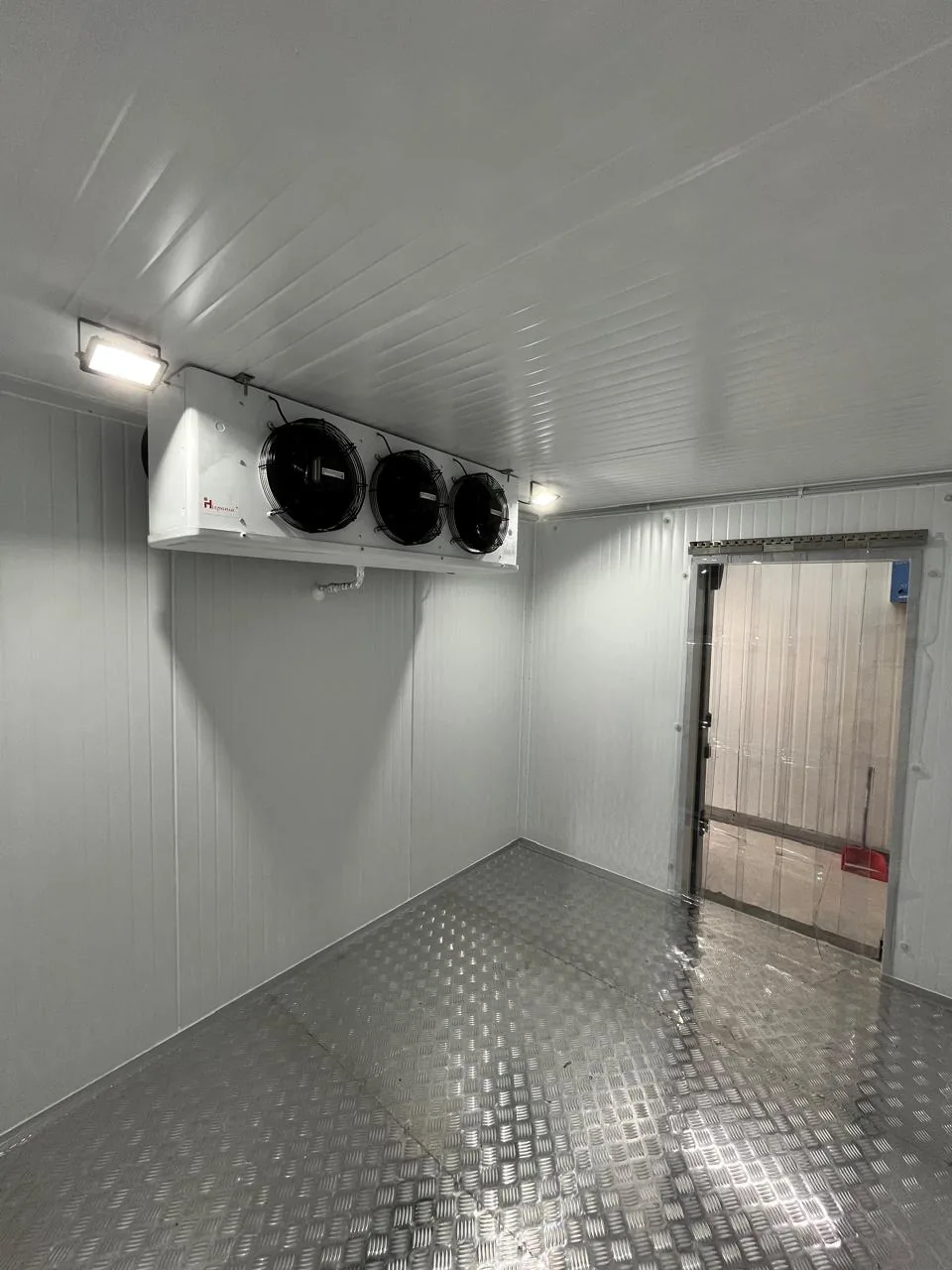 Interior de una cámara frigorífica comercial terminada, con evaporador y cortina de lamas