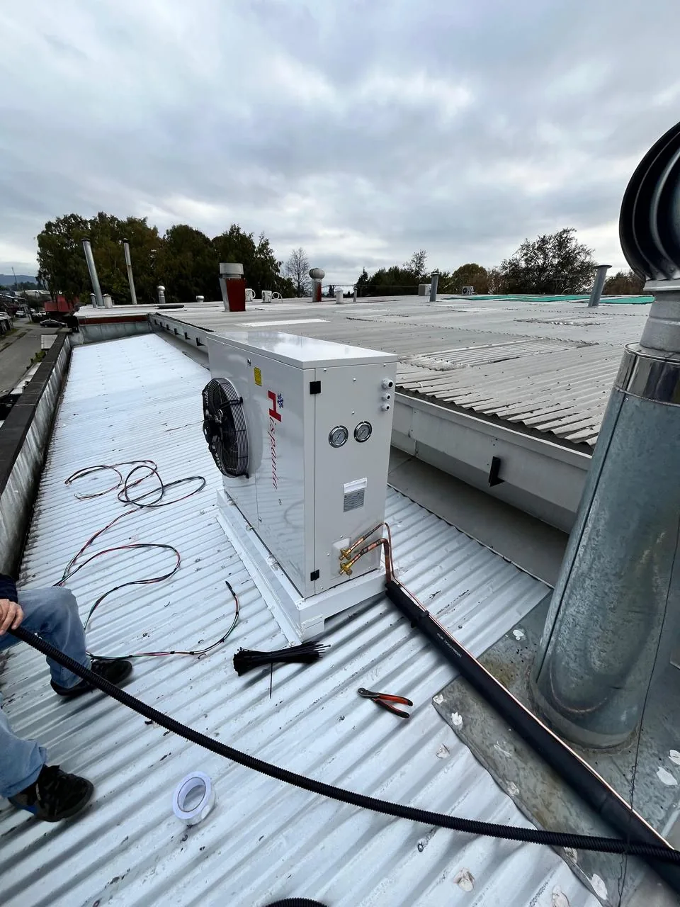 Unidad condensadora instalada sobre la cubierta del edificio con la ciudad al fondo