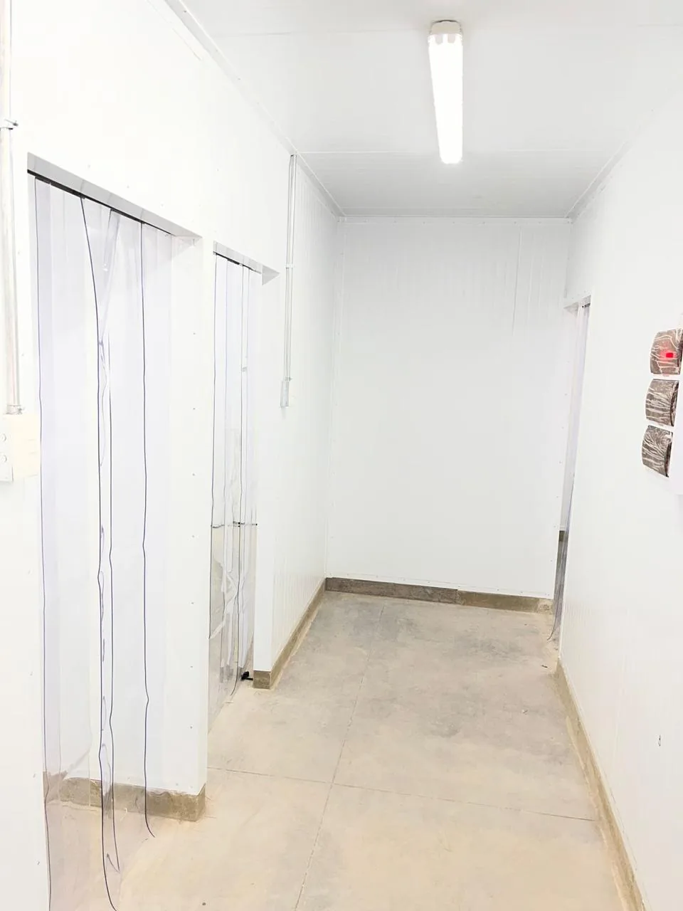 Pasillo de panel blanco entre dos cámaras frigoríficas con cortinas de lamas